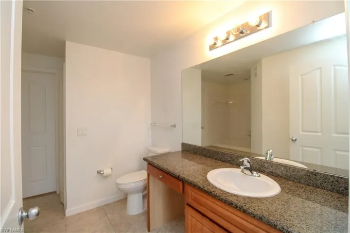 Bathroom featuring tile patterned floors, a shower, vanity, and toilet