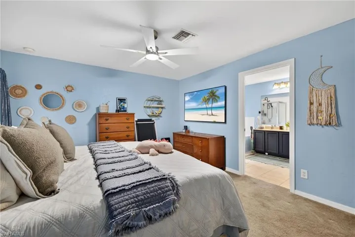 Carpeted bedroom with ceiling fan and connected bathroom