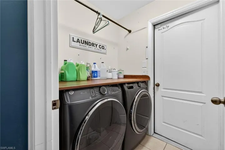 Laundry room featuring light tile patterned floors and washing machine and dryer