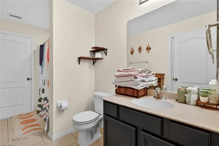 Bathroom with curtained shower, light tile patterned floors, and vanity