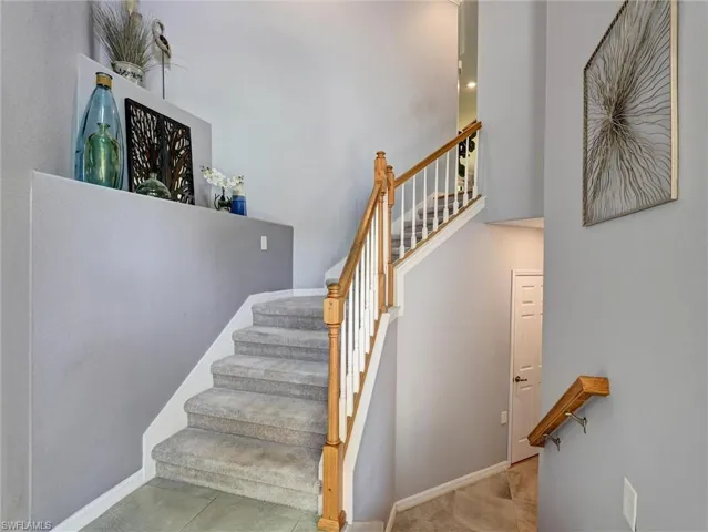 Carpeted staircase featuring a light wood handrail and white balusters