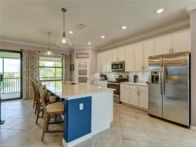 Kitchen featuring a large central island with seating, stainless steel appliances, white shaker cabinetry, tiled backsplash, and recessed lighting