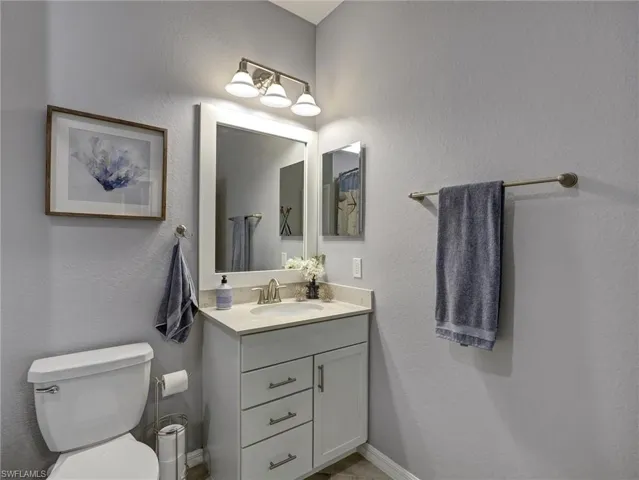 Bathroom vanity featuring a single basin sink, light-toned countertop, and cabinet storage with drawers