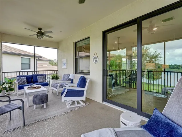 Spacious screened lanai featuring an outdoor ceiling fan, large sliding glass doors, a window, and black railing overlooking a body of water