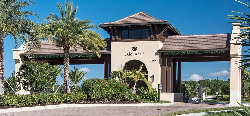 Community entrance featuring a multi-story gatehouse with a tiled roof and stucco exterior
