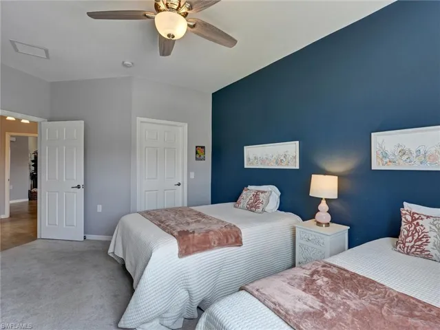Interior space featuring a vaulted ceiling with a ceiling fan, carpeted flooring, and a deep blue accent wall