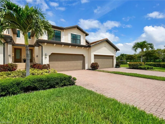 Stucco exterior residence featuring a tiled roof, two-car garage, and a paver driveway