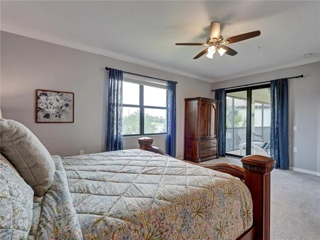 Bedroom featuring a ceiling fan, crown molding, double windows, and sliding glass doors to an outdoor screened area