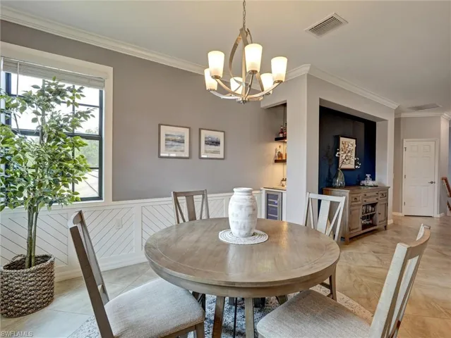 Dining area featuring a circular wood-finish table, a five-light chandelier, and wainscoting with a diagonal pattern