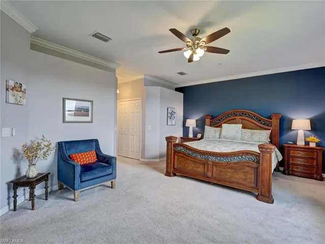 Carpeted room featuring crown molding, a decorative ceiling fan, and a built-in double-door closet