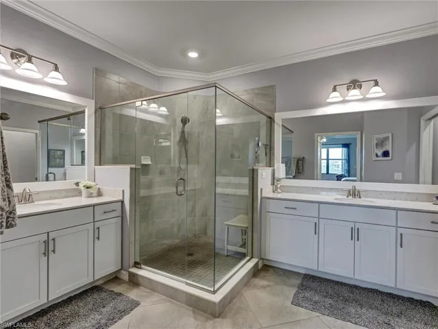 Dual vanity bathroom featuring a glass-enclosed shower with tile surround