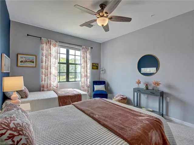 Bedroom featuring a window with natural light, a ceiling fan with integrated lighting, and carpeted flooring