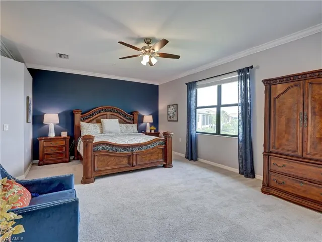 Spacious bedroom featuring plush carpeting, a large window, and crown molding