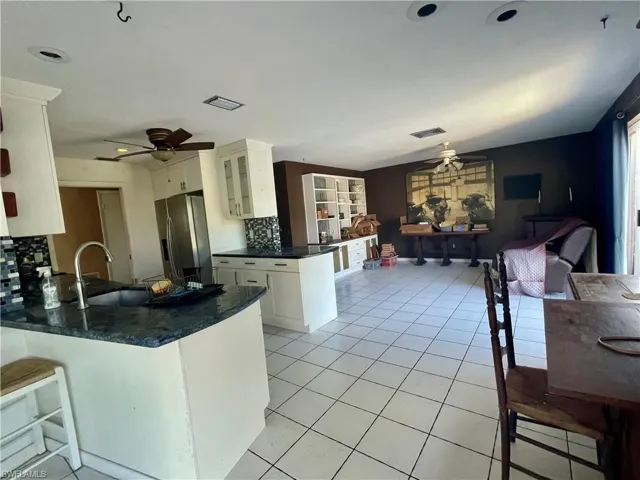 Kitchen featuring white cabinetry, ceiling fan, kitchen peninsula, and stainless steel refrigerator with ice dispenser