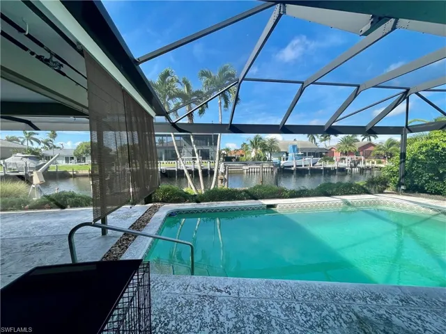 View of swimming pool featuring glass enclosure and a water view