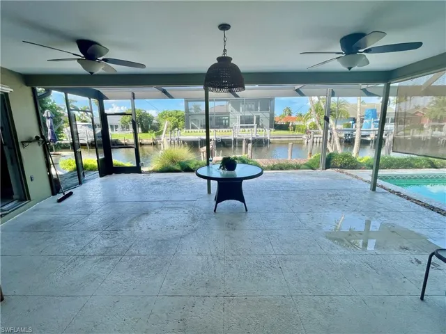 Unfurnished sunroom with ceiling fan and a water view