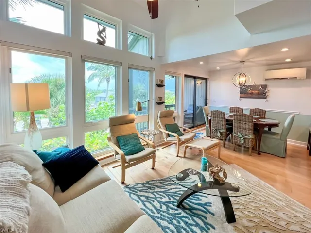 Living room with a wall unit AC, hardwood / wood-style flooring, plenty of natural light, and a towering ceiling
