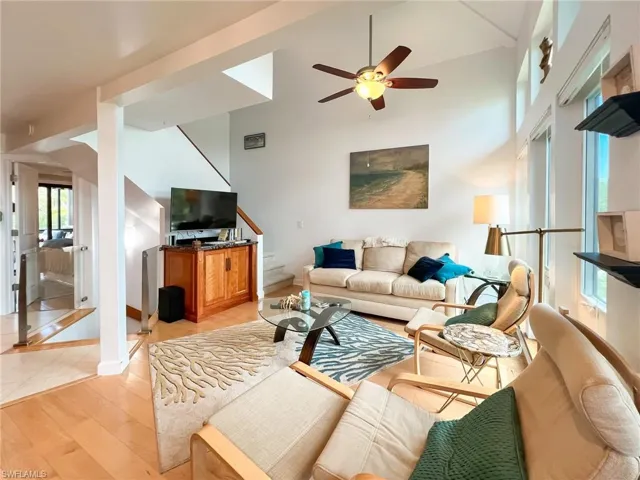 Living room with a towering ceiling, ceiling fan, and light hardwood / wood-style flooring