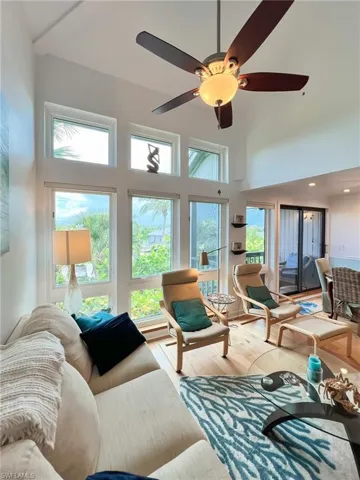Living room with a towering ceiling, ceiling fan, and light hardwood / wood-style flooring