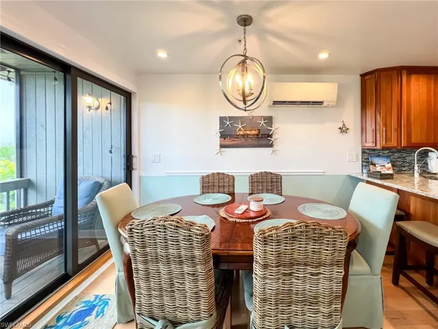 Dining area featuring a chandelier, sink, a wall unit AC, and light wood-type flooring