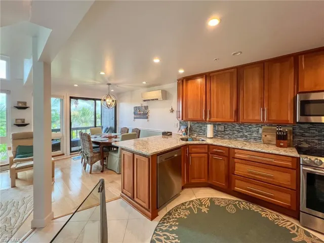 Kitchen featuring light stone counters, light hardwood / wood-style floors, kitchen peninsula, backsplash, and appliances with stainless steel finishes