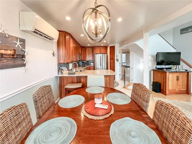 Dining area featuring a notable chandelier, a wall unit AC, and sink