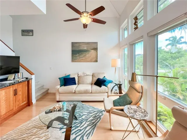 Living room featuring a towering ceiling, ceiling fan, and light hardwood / wood-style flooring
