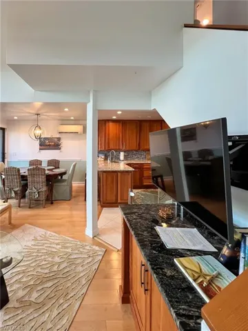 Kitchen with decorative light fixtures, dark stone counters, tasteful backsplash, and an AC wall unit