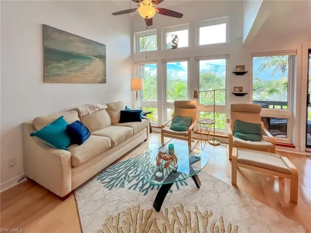 Living room featuring hardwood / wood-style floors, a high ceiling, and ceiling fan