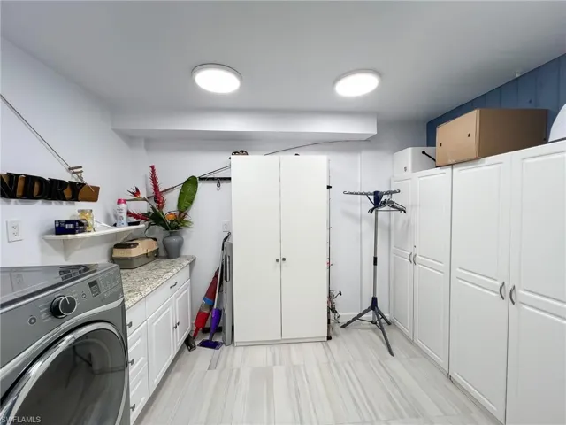 Washroom featuring cabinets, washer / dryer, and light tile floors