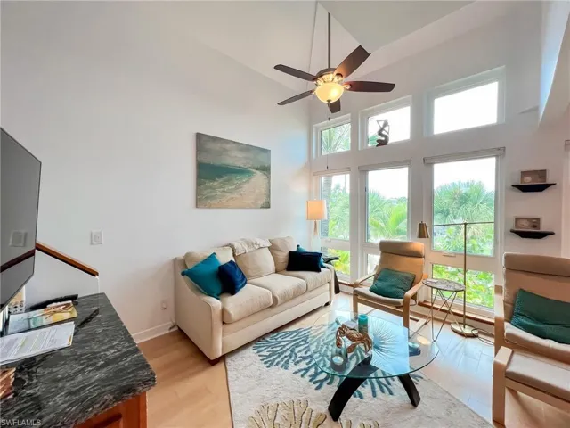 Living room with high vaulted ceiling, light hardwood / wood-style floors, plenty of natural light, and ceiling fan