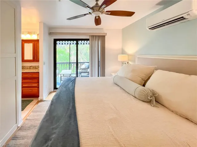 Bedroom featuring hardwood / wood-style flooring, ceiling fan, an AC wall unit, and access to outside