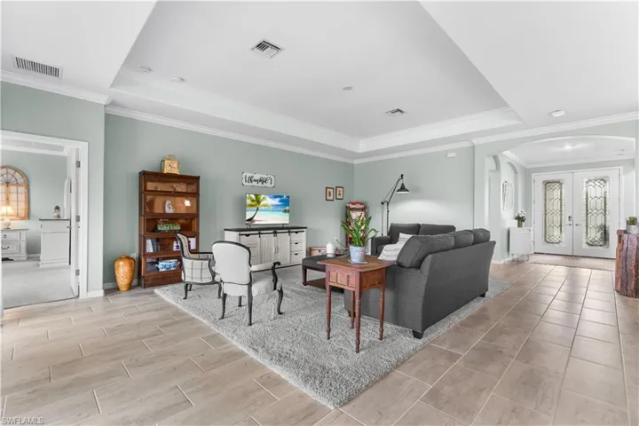 Living room featuring a tray ceiling, french doors, and crown molding