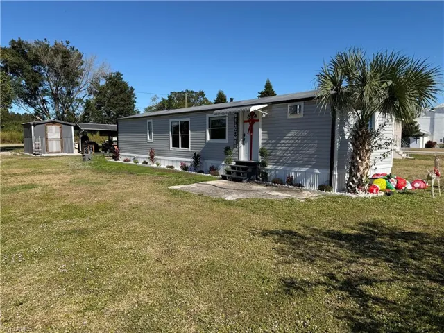 Rear view of house with entry steps, a yard, and a storage unit