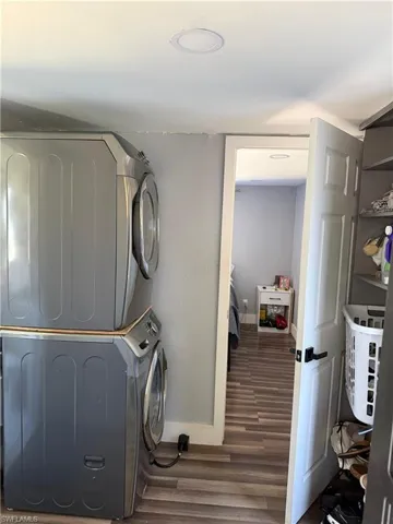 Laundry area featuring stacked washer and clothes dryer and wood finished floors