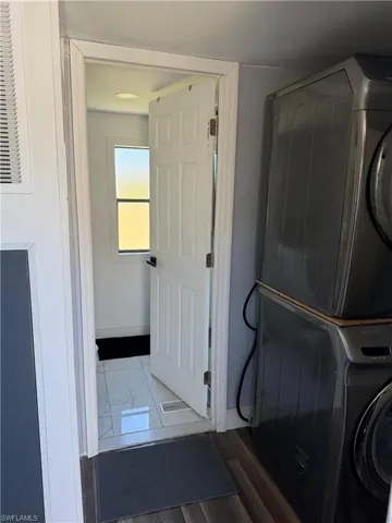 Laundry area with estacked washer and dryer and dark marble finish flooring