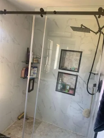 Full bath featuring a marble finish shower