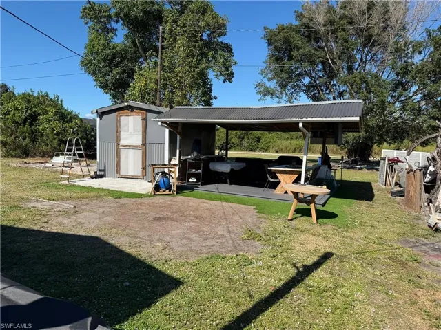 View of grassy yard with a patio area and a storage unit