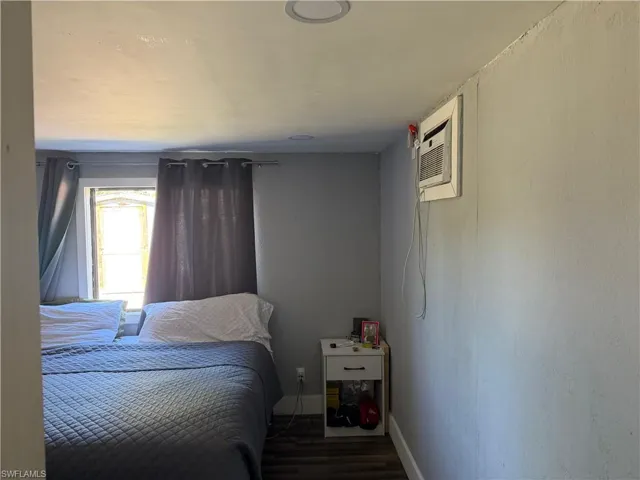 Bedroom with a wall mounted AC and wood finished floors