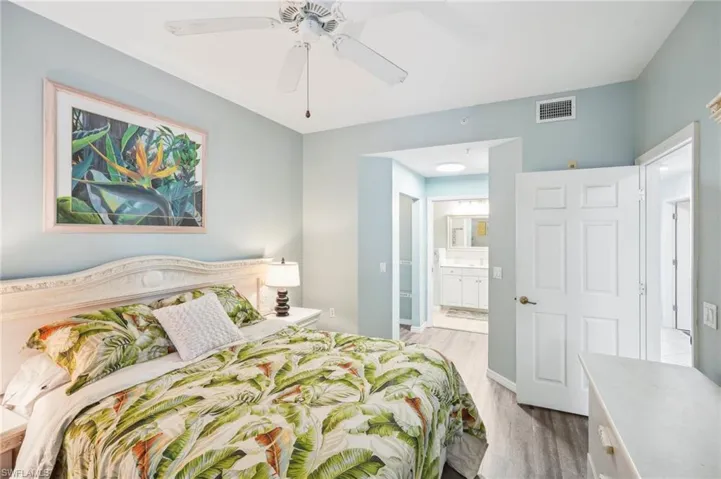 Bedroom with light hardwood / wood-style flooring, ceiling fan, and ensuite bath
