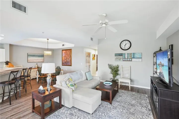 Living room with hardwood / wood-style flooring, ceiling fan, and a raised ceiling