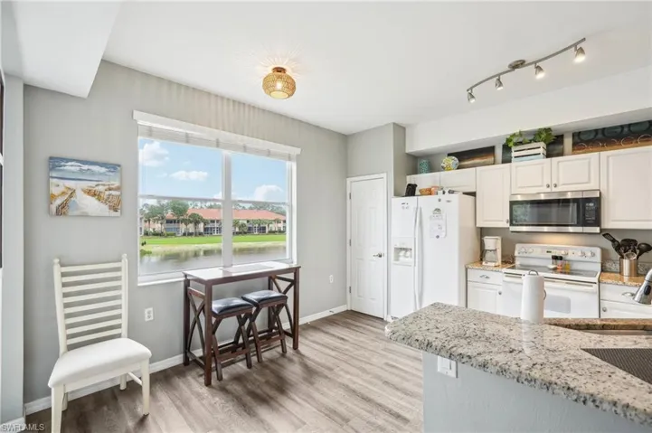 Kitchen featuring white cabinetry, white appliances, light stone counters, and a water view