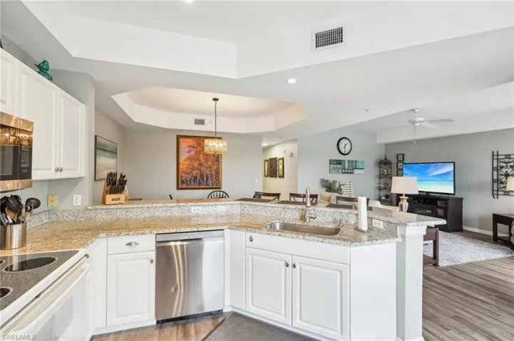 Kitchen featuring sink, white cabinetry, stainless steel appliances, kitchen peninsula, and a raised ceiling