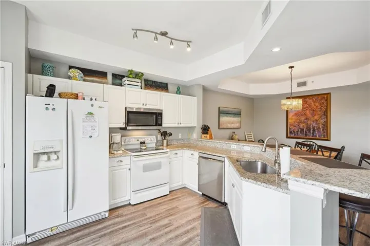 Kitchen with stainless steel appliances, a tray ceiling, kitchen peninsula, and a breakfast bar area