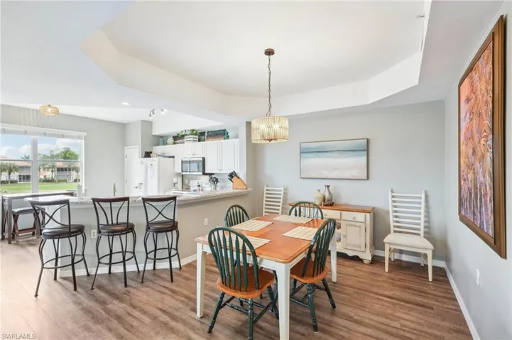 Dining space with an inviting chandelier, light hardwood / wood-style flooring, and a raised ceiling