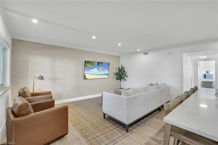 Living room with crown molding, recessed lighting, and light wood finished floors