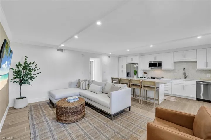 Living area featuring wood tiled floors, crown molding, and recessed lighting
