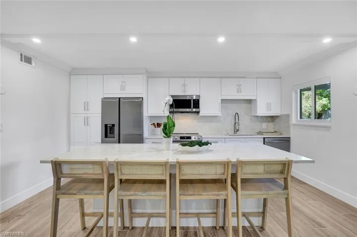 Kitchen with white cabinetry, stainless steel appliances, light wood-style flooring, and recessed lighting