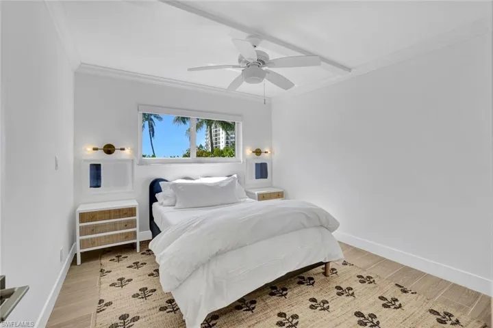 Bedroom with crown molding, light wood finished floors, and a ceiling fan