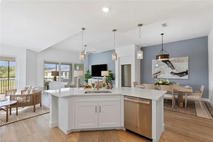 Kitchen featuring light wood-type flooring, white cabinets, sink, decorative light fixtures, and dishwasher